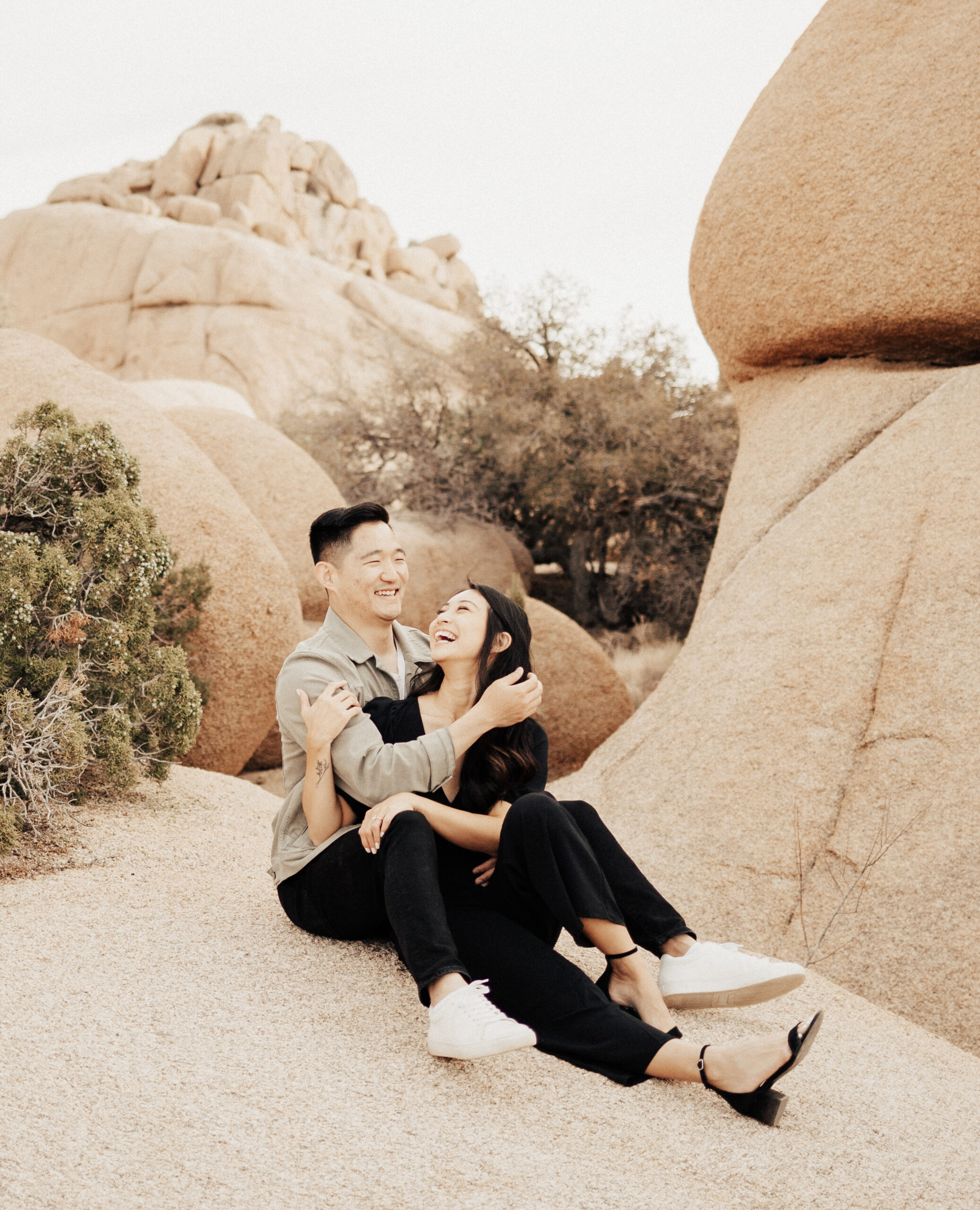 Engaged Couple Sitting on Rocks Laughs
