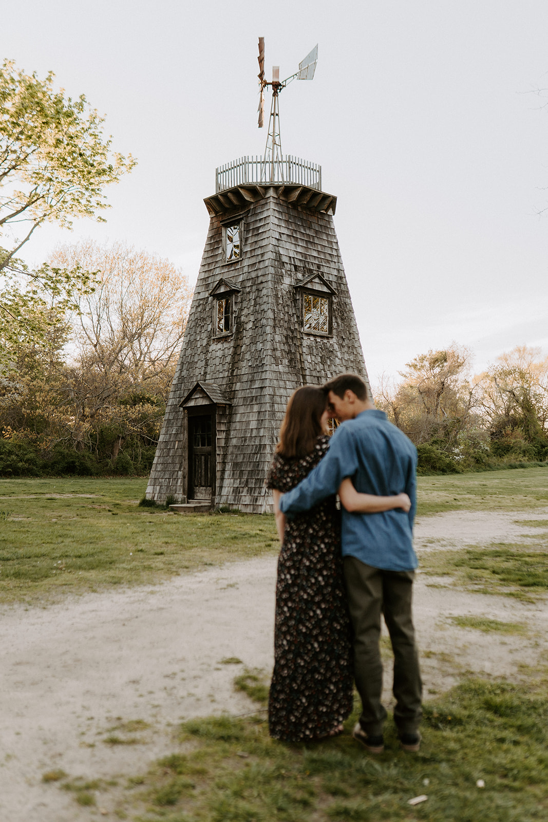 couple hugging in front of light house during engagement session